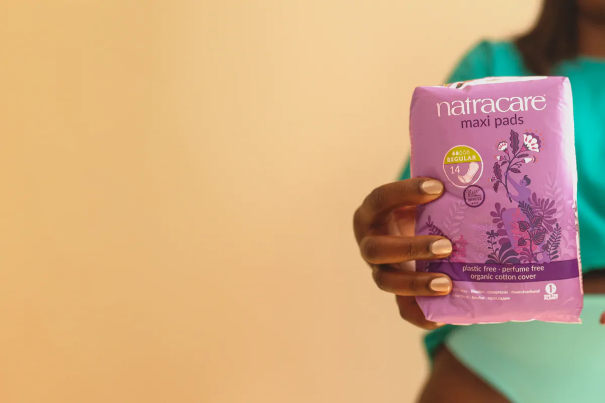 woman holding a pack of natracare maxi and ultra pads