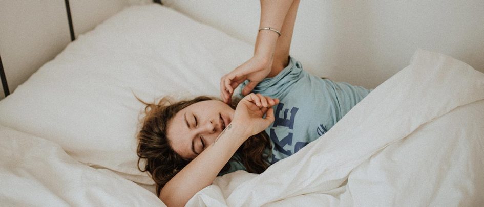 girl stretching half asleep in bed