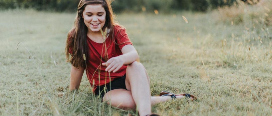 Adolescente se sentó sonriendo en un campo