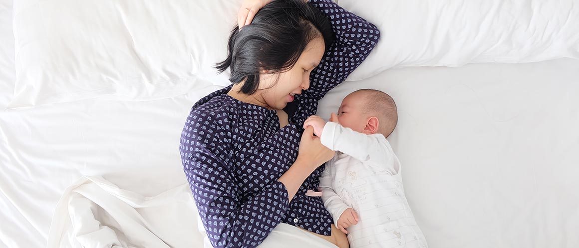 woman and her baby lying on bed