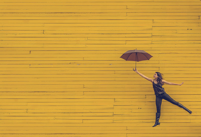 Woman with umbrella on yellow background