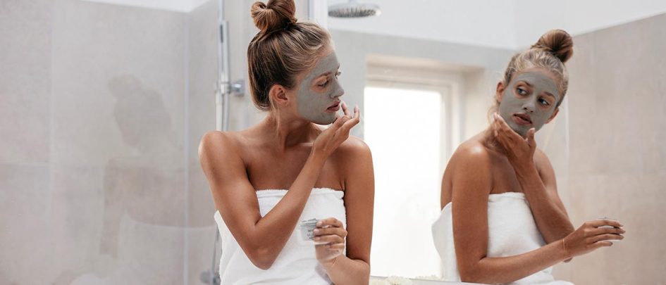 woman doing face mask in mirror