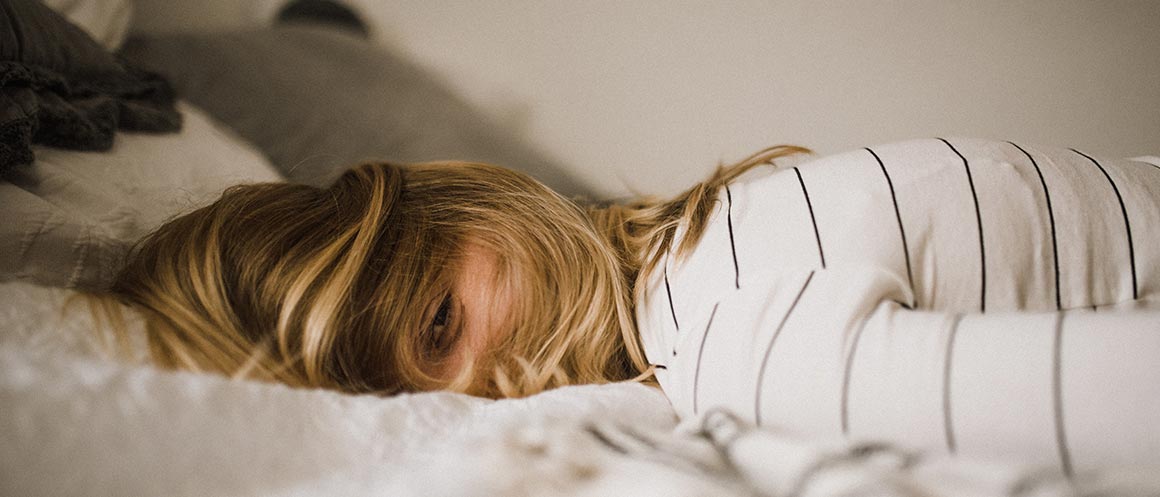 tired woman lying face down on bed