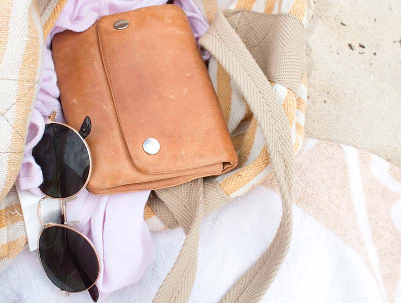 Sunglasses and leather pouch on beach