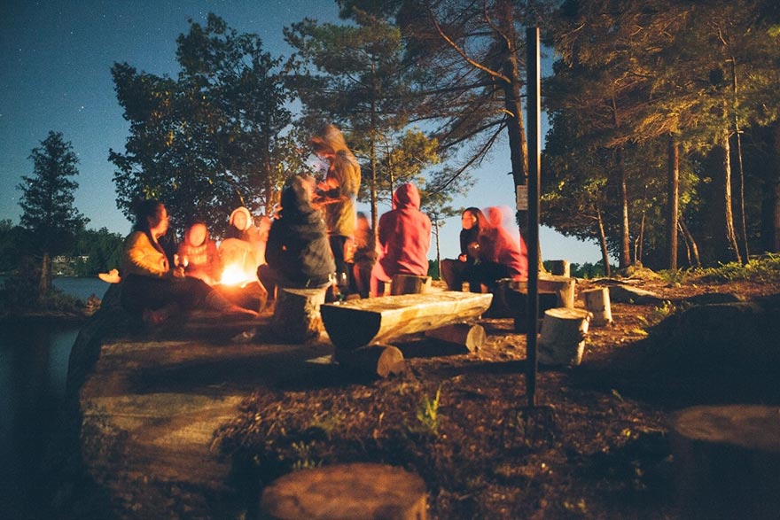 pessoas sentadas no acampamento ao pé da lareira