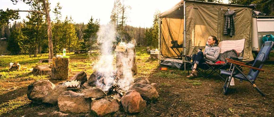 woman sat by campsite fire