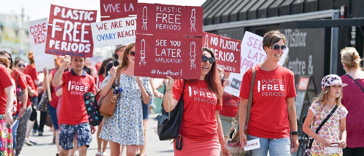 people holding banners for plastic free periods protest