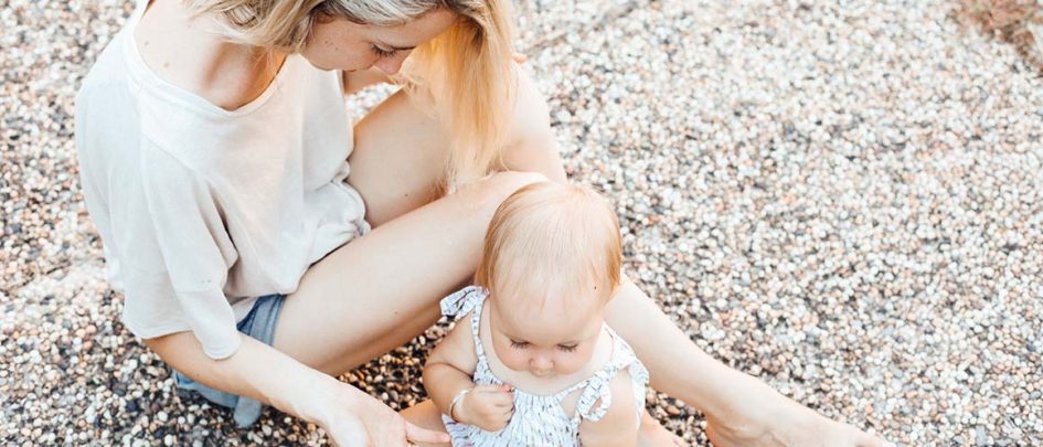 Frau sitzt mit Baby auf dem Boden