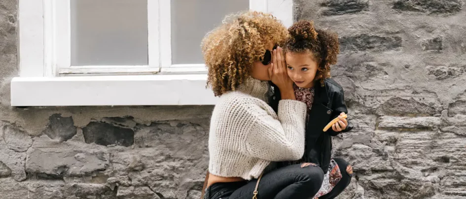 woman whispering in young girl's ear