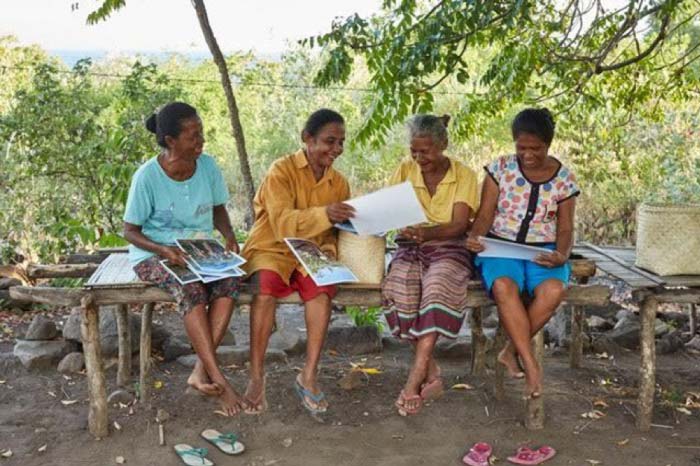 women sat on bench looking at photographs