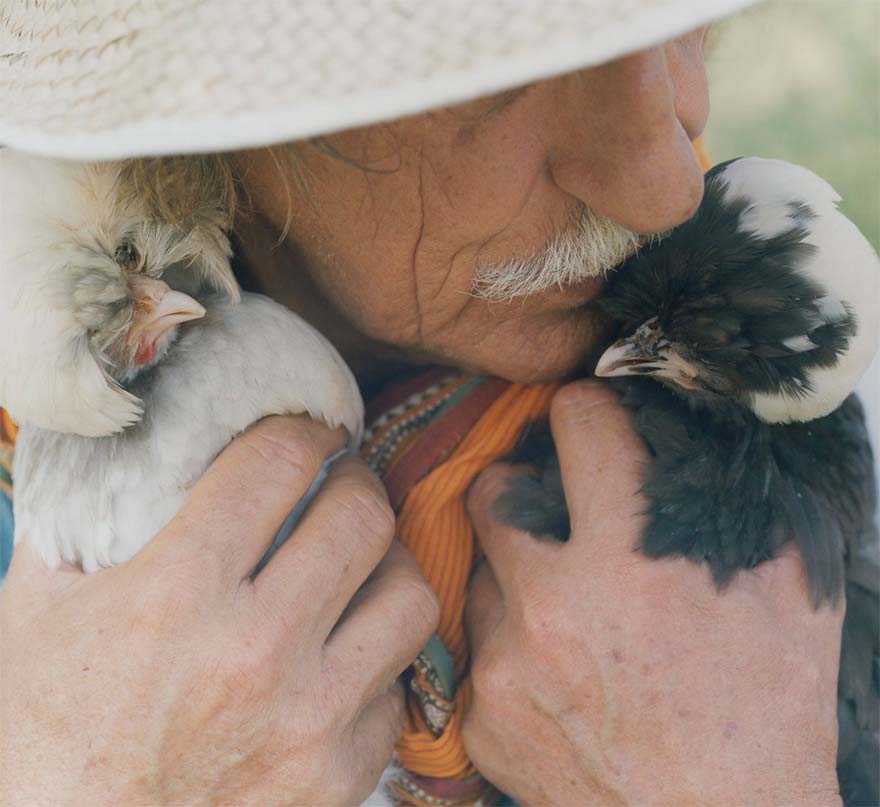 man holding and kissing two chickens