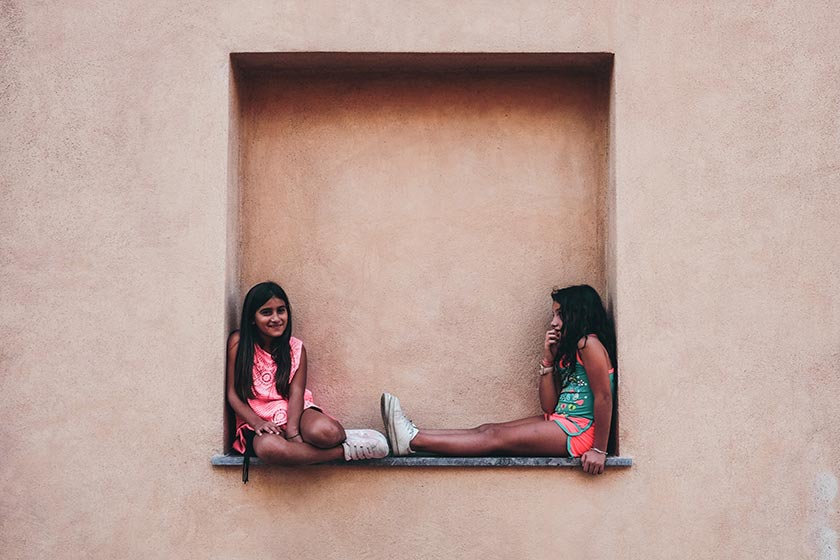 Two young girls sitting on a wall