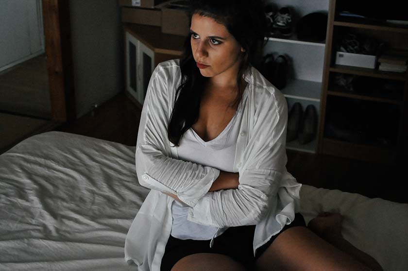 Woman sitting on bed looking grumpy