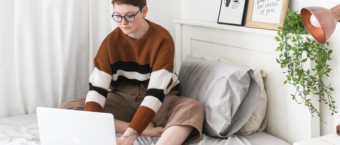 woman sat on bed browsing on laptop