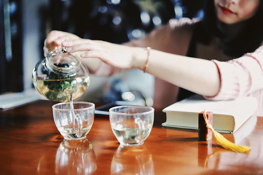 pouring tea into glass teacup