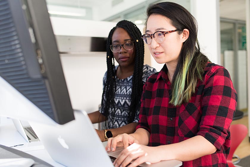 two women working at laptops