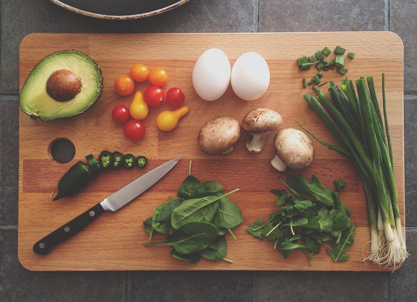 Ingredientes en una tabla de cortar: huevos, cebollas, aguacate