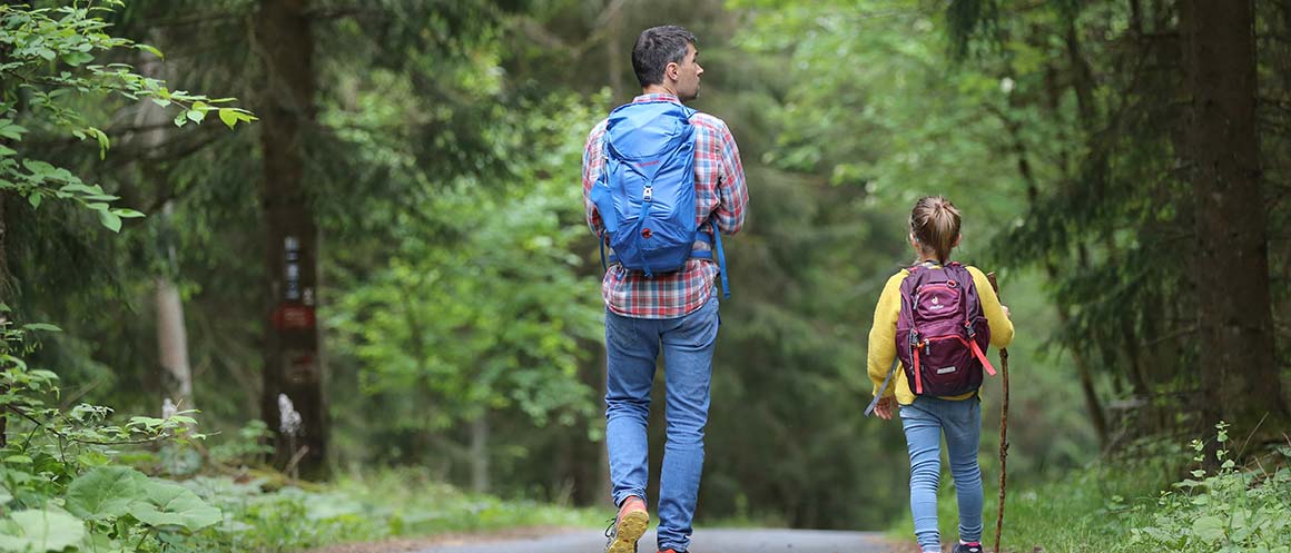 father and daughter walking in nature with rucksacks