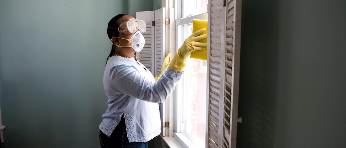masked woman cleaning windows