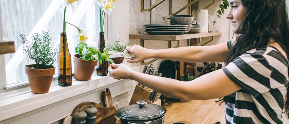 woman pruning kitchen windowsill plants