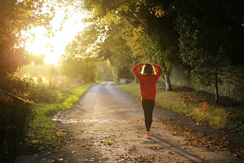 Femme faisant une promenade matinale avec des arbres et du soleil