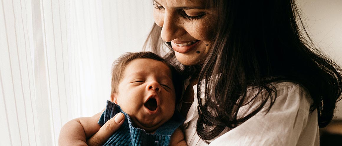 ein Elternteil, der tagsüber ein gähnendes Baby hält