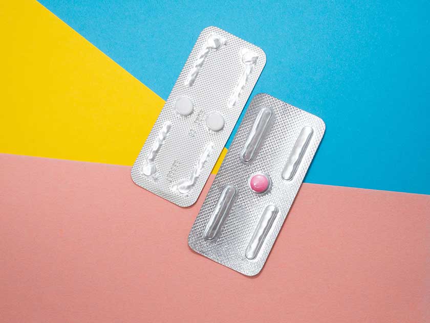 Picture of a pink pill in a packet against a blue, yellow and pink background