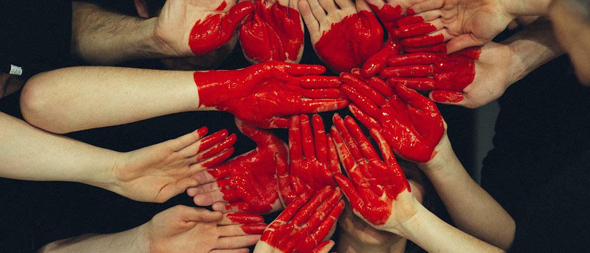 Hands with red paint making heart shape