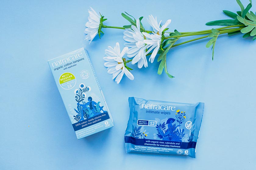 Tampons und Intimpflegetücher im neuen Natracare Design mit weiße Blumen daneben