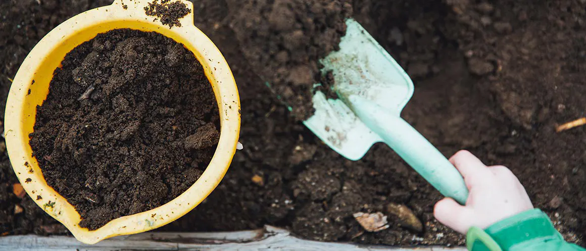 person with bucket and spade composting