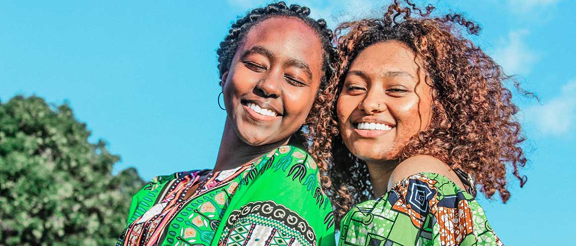 two people standing in the sun smiling with blue sky