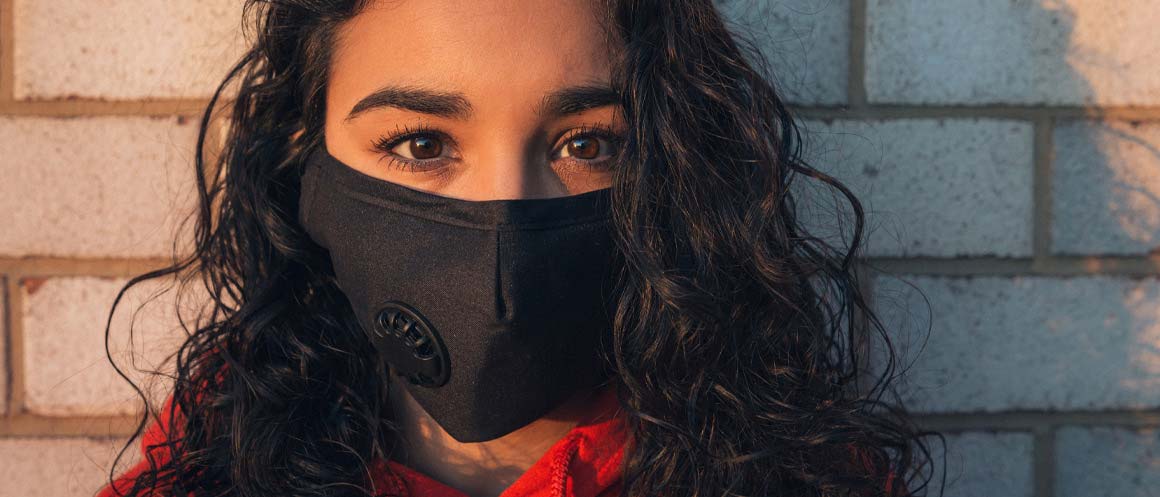 person stood in front of a brick wall wearing a face mask