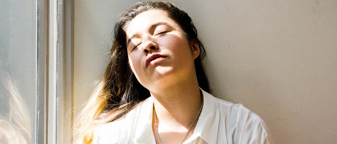 Vrouw rust met haar hoofd op de muur, verlicht door de zon