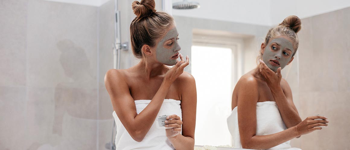 mujer haciéndose una mascarilla en el espejo