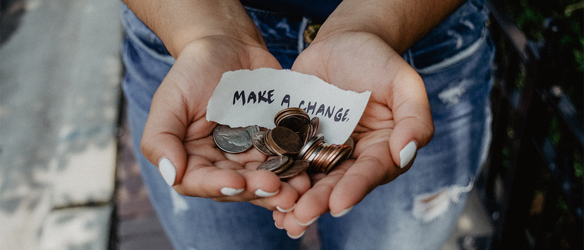 Charitable Giving. Hands holding coins with a note that says 'make a change'.