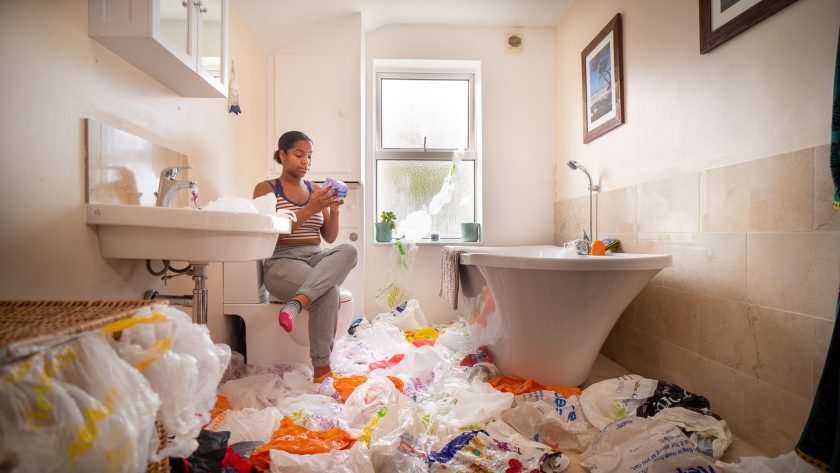 person sitting amongst plastic bathroom waste